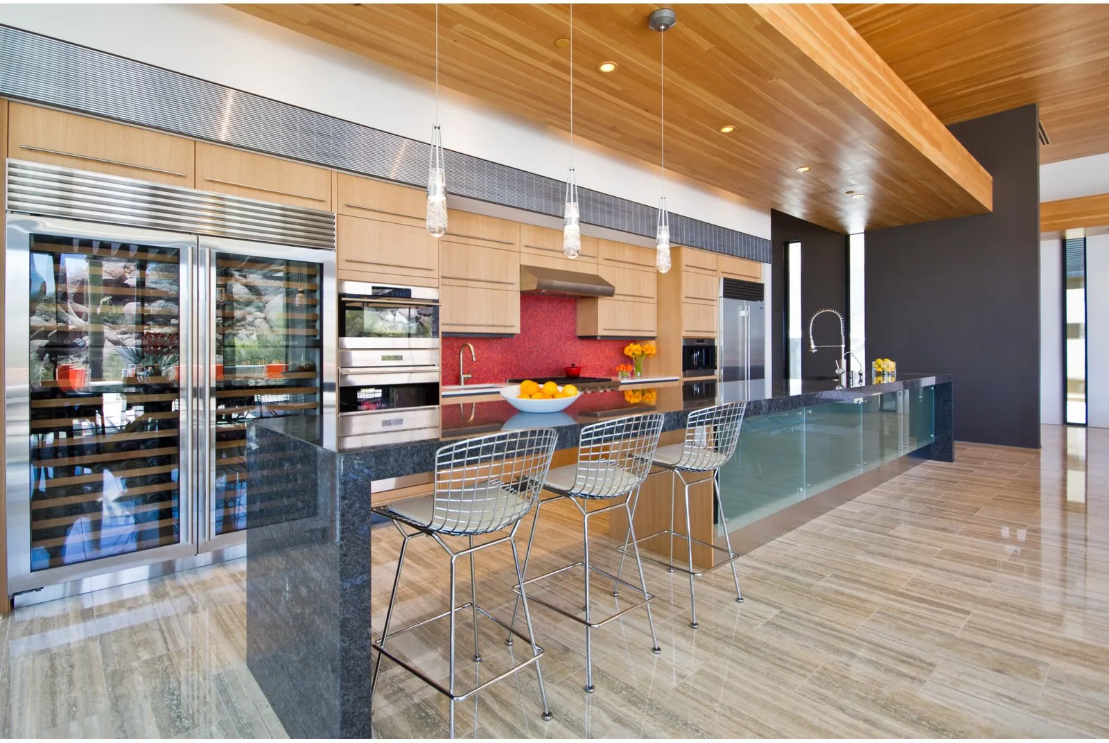 A contemporary kitchen with a full-height stone backsplash and travertine floor, set by Southwestern Tile Installations.