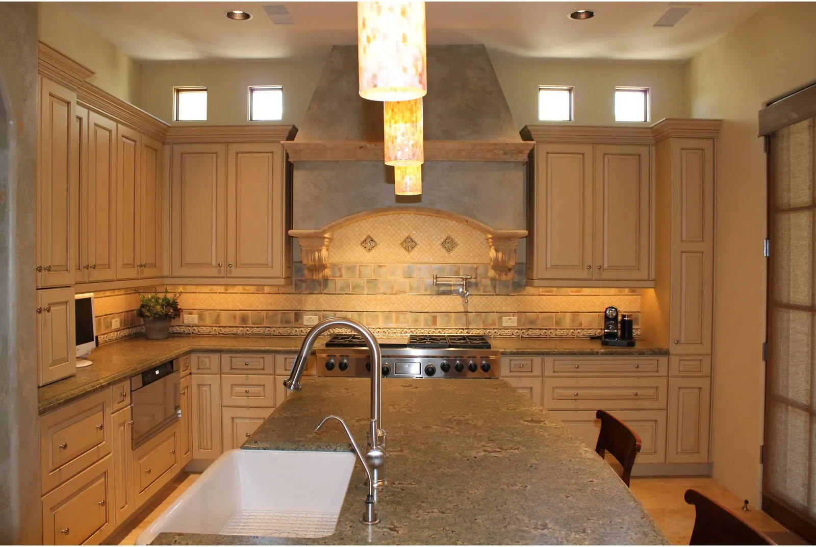 Contemporary kitchen with a tiled island wall and patterned backsplash by Southwestern Tile.
